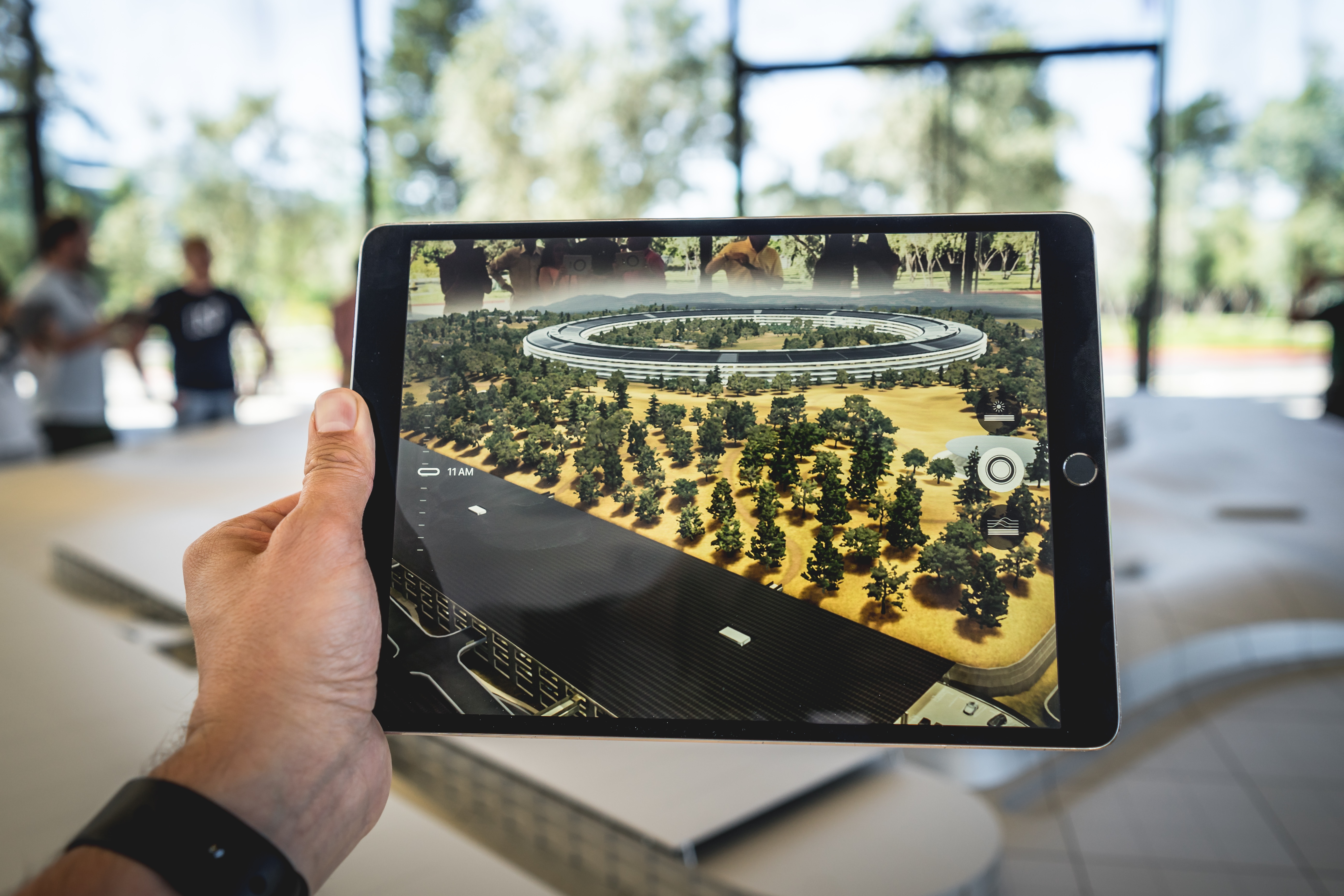 A hand holding a tablet with a screen showing a road and treesDescription automatically generated
