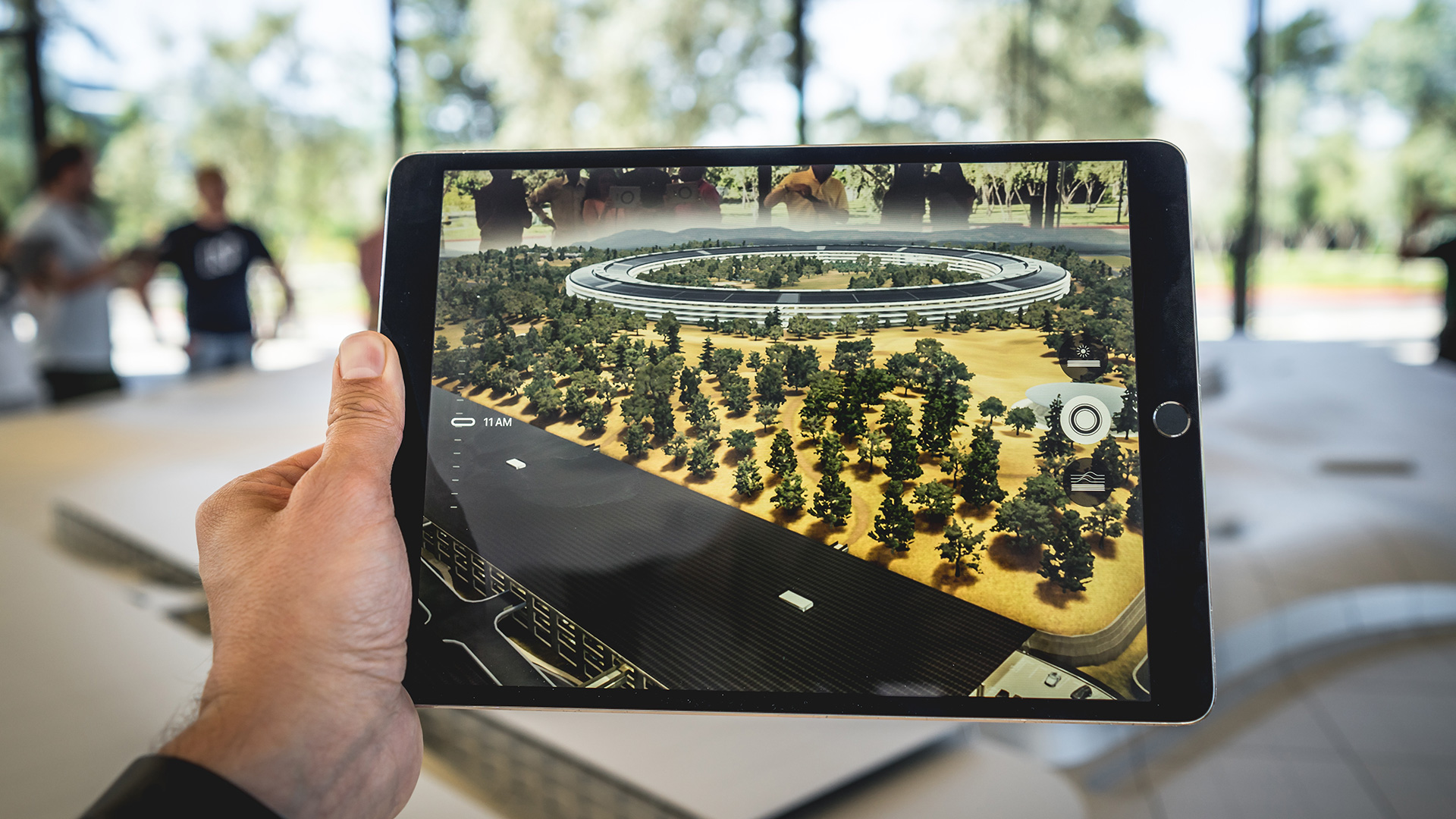 A hand holding a tablet with a screen showing a road and treesDescription automatically generated