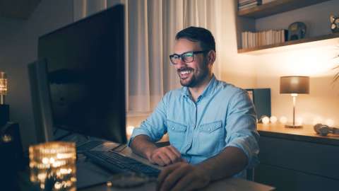 Man with a blue shirt working with a PC at night