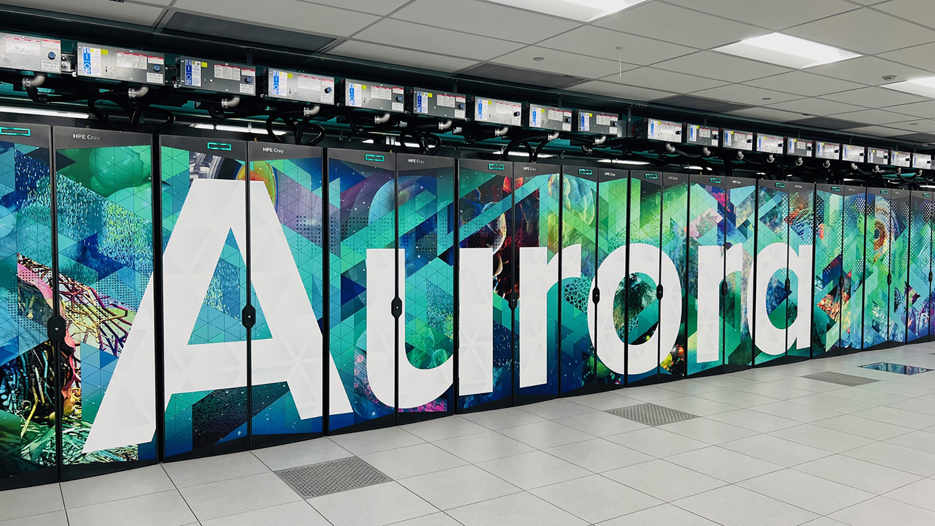 Aurora Supercomputer racks at Argonne National Laboratory featuring large 'Aurora' lettering and colorful graphics.