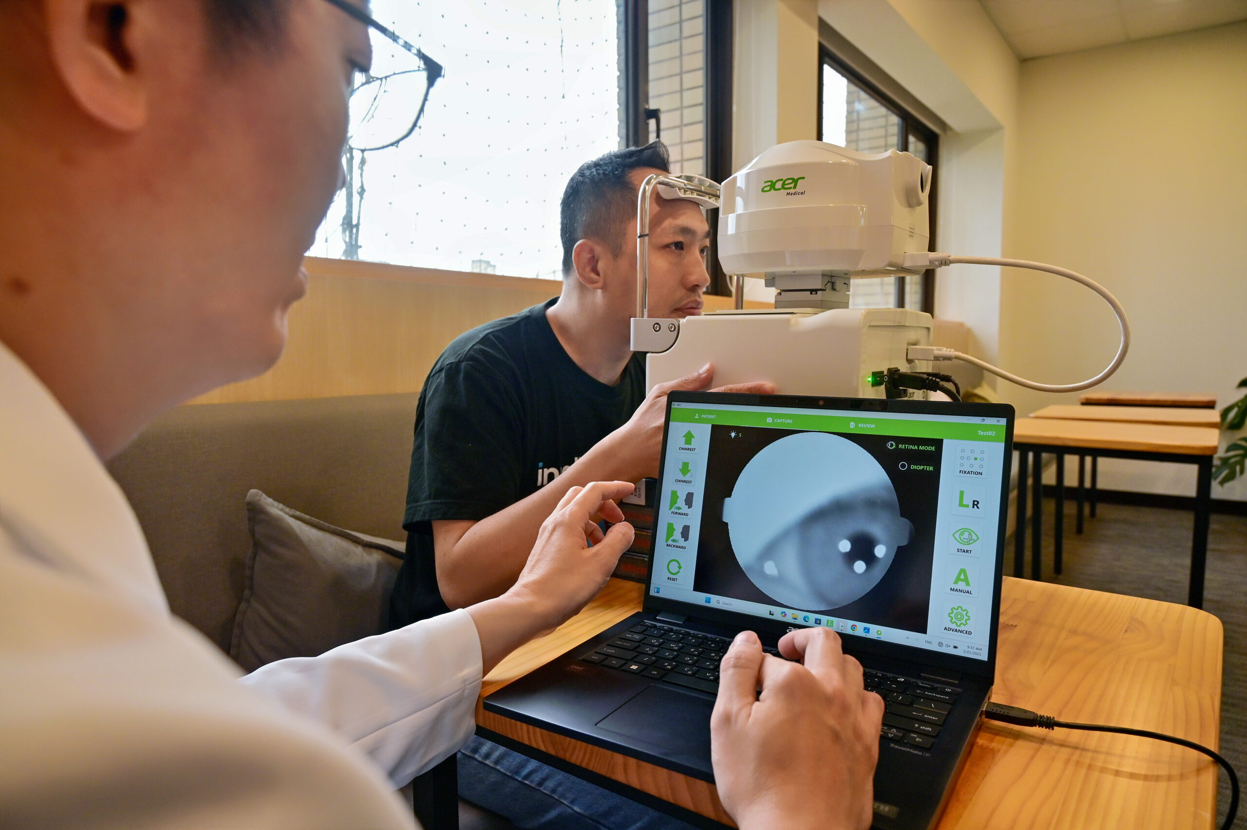 Dr. Hsieh Yi-Ting reviews a patient's eye scan on a laptop connected to a fundus camera.