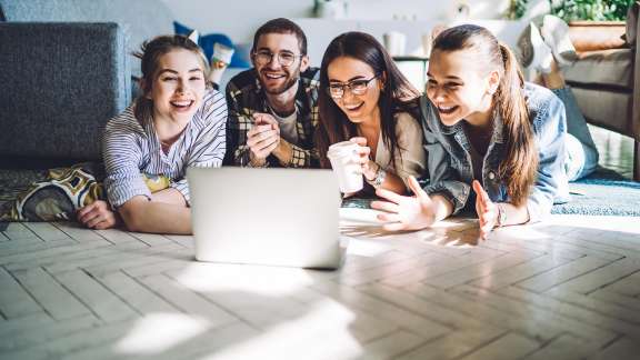 Happy teens having fun looking at laptop on floor of family room