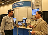 David Reeder, cq, of Airspan Networks, Inc., left, talks with Steven Eliscu, cq, UBS financial analyst, right, about the expected growth of the WiMax market in the next several years in front of the Intel PRO/Wireless 5116 Broadband interface booth in the Tech Showcase at the Fall Intel Developer Forum held at Moscone West on Tuesday, August 23, 2005 in San Francisco, Calif. (Photo by Intel Press Relations)